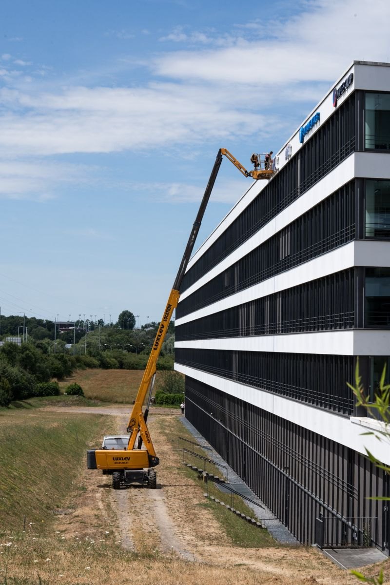 Nacelle télescopique LUXLEV déployée le long de la façade d'un bâtiment de Technopolis pour la pose d'une enseigne